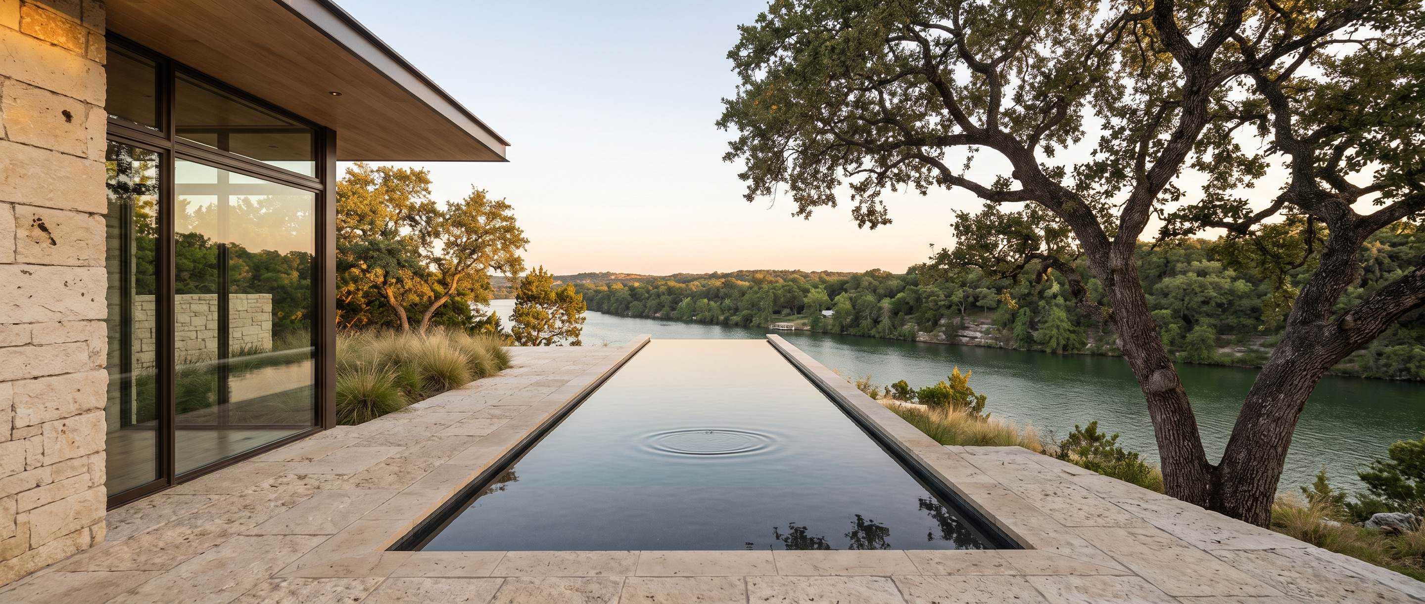 A limestone terrace and dark bottomed lap pool running along the bluff edge, the green lake far below.